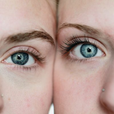 sharon-mccutcheon-NeRKgBUUDjM-unsplash.jpg Bild von zwei Frauen die ihre Köpfe seitlich aneinander drücken. Man sieht in der Bildmitte die Augen und jeweils rechts und links eine Gesichtshälfte der jeweiligen Frauen.